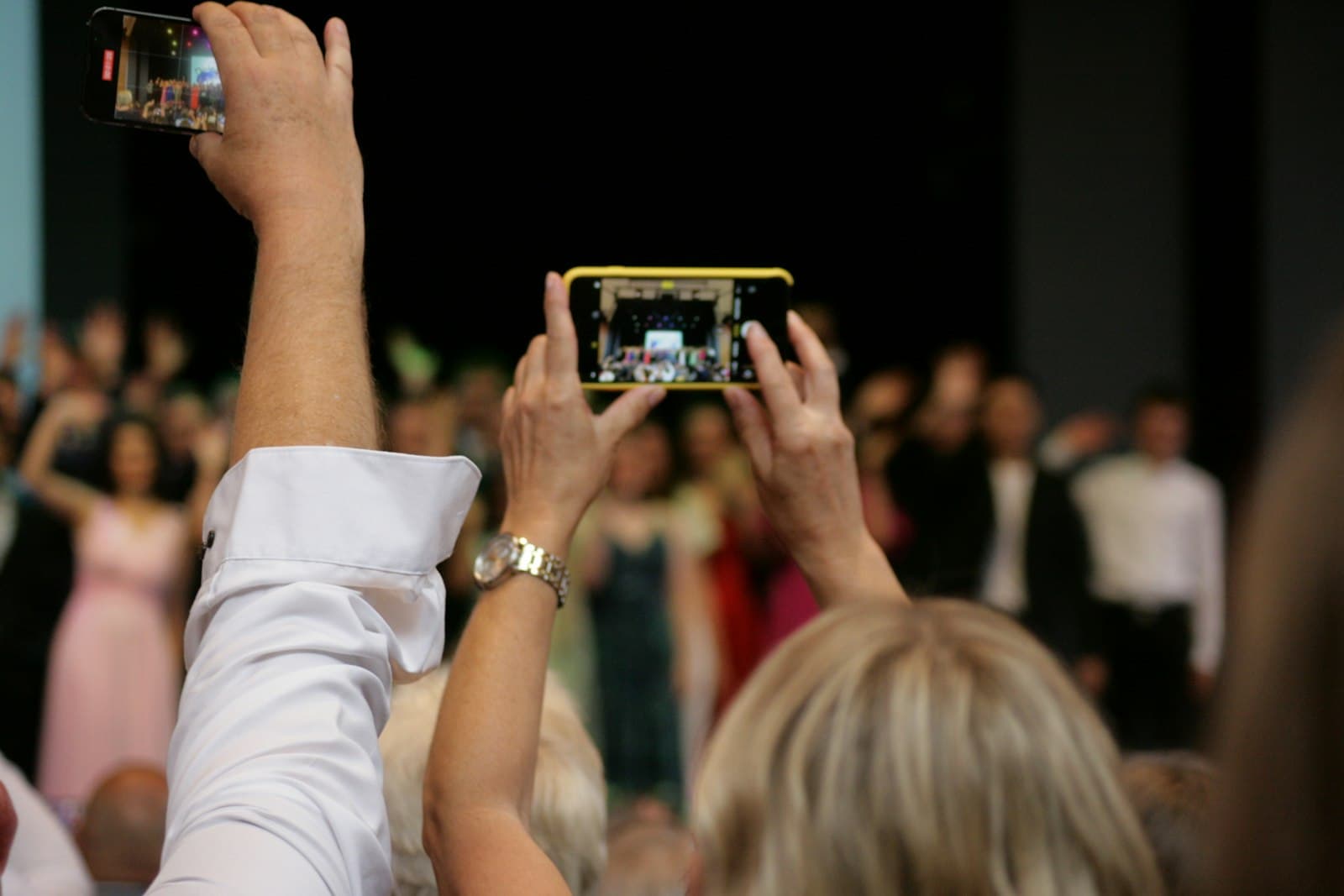Wedding guests holding up their phones to photograph the couple