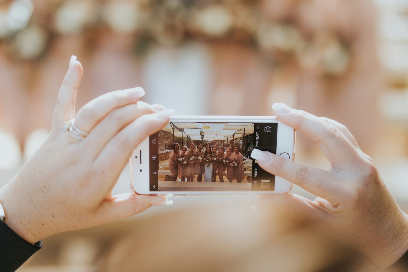 Two hands holding a phone, the screen showing a just-taken photo of the bridal party
